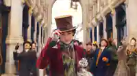 Wonka (Timothee Chalament) steht vor einer begeisterten Menschenmenge und fasst sich an seinen Hut. 