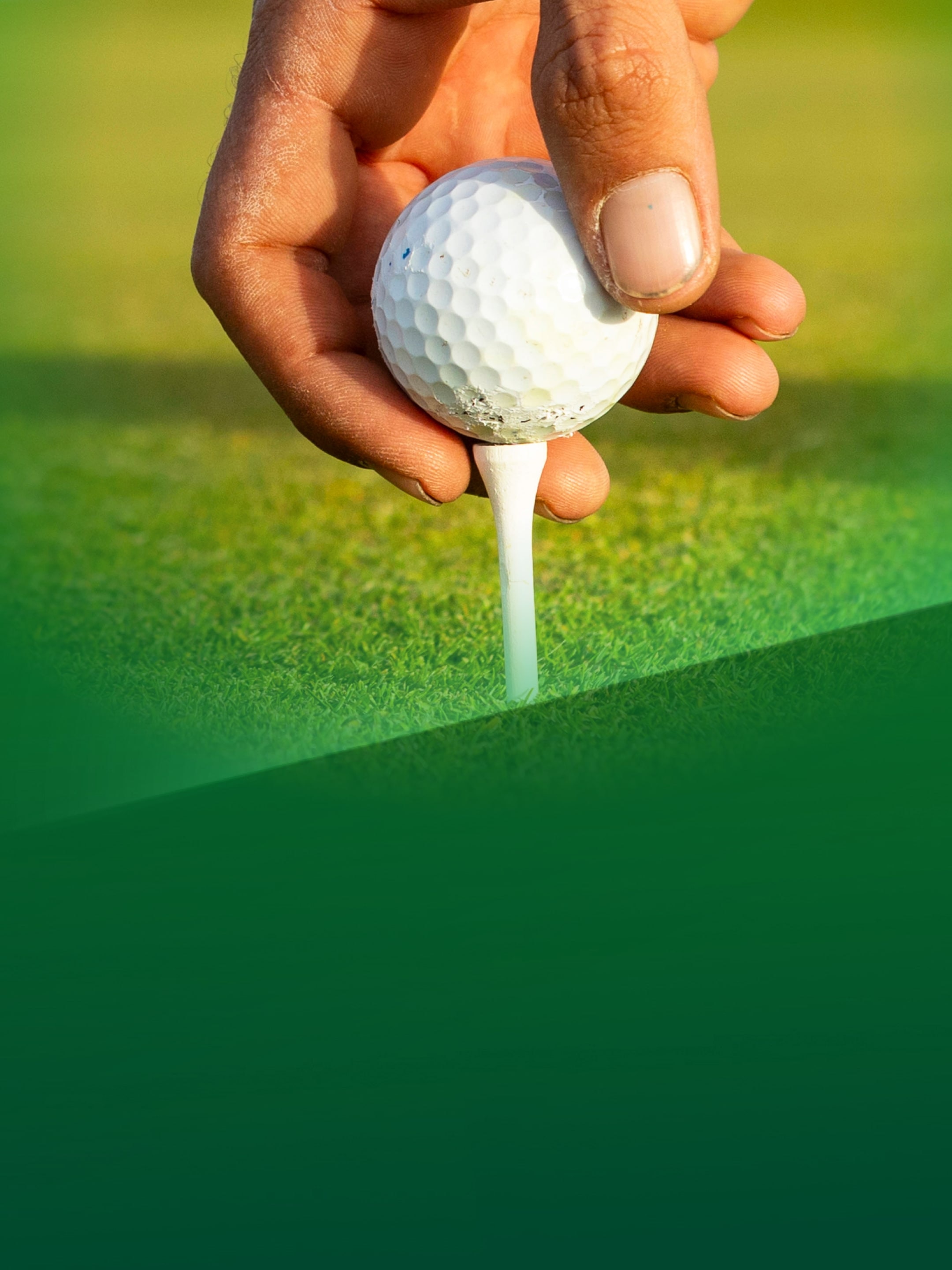 Eine Hnad legt einen Golfball auf einen Tee. 