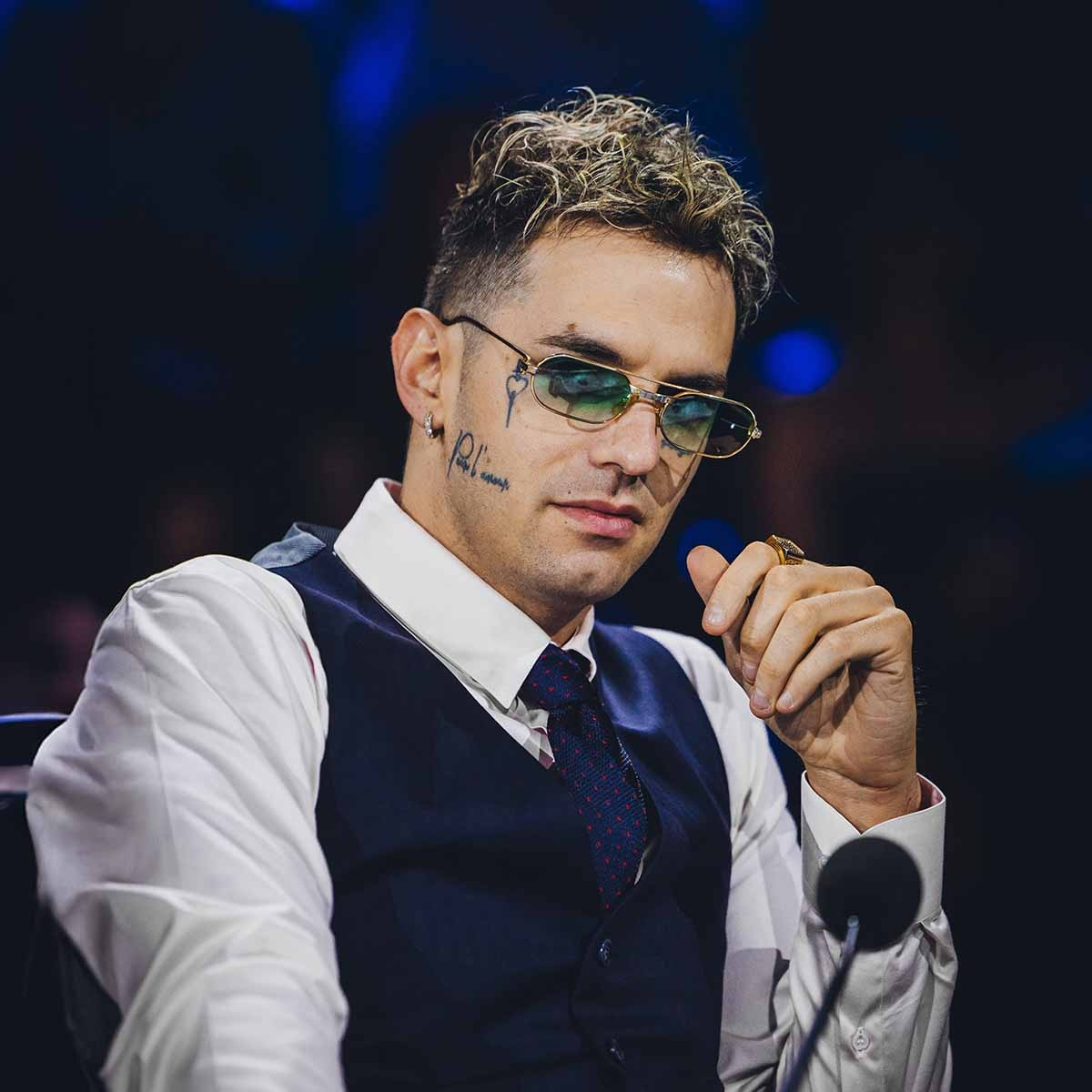 Achille Lauro in giacca elegante e occhiali da sole seduto come giudice a X Factor 2024